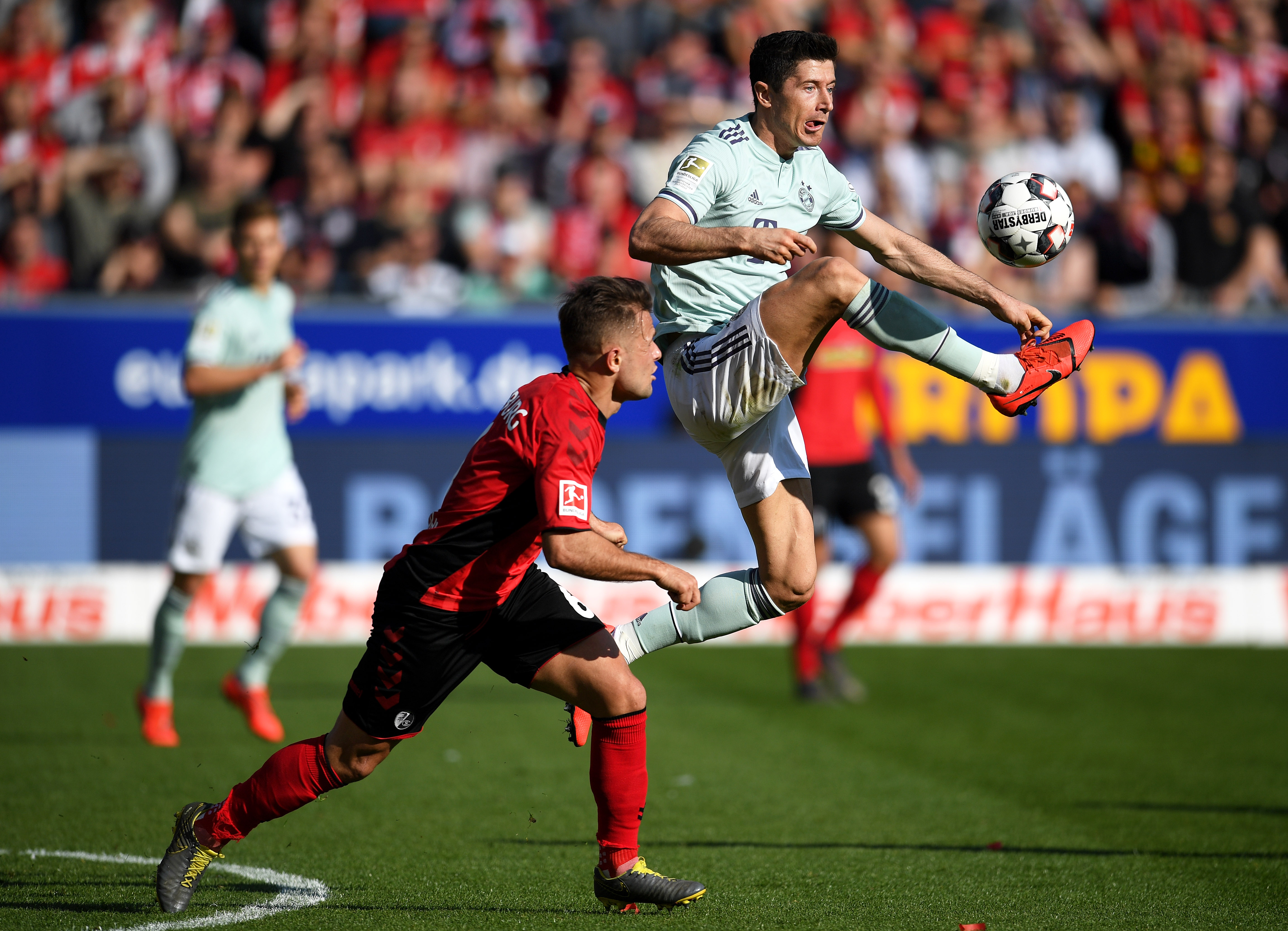 FREIBURG IM BREISGAU, GERMANY - MARCH 30: Robert Lewandowski of Bayern Munich controls the ball under pressure from Amir Abrashi of Freiburg during the Bundesliga match between Sport-Club Freiburg and FC Bayern Muenchen at Schwarzwald-Stadion on March 30, 2019 in Freiburg im Breisgau, Germany. (Photo by Matthias Hangst/Bongarts/Getty Images)